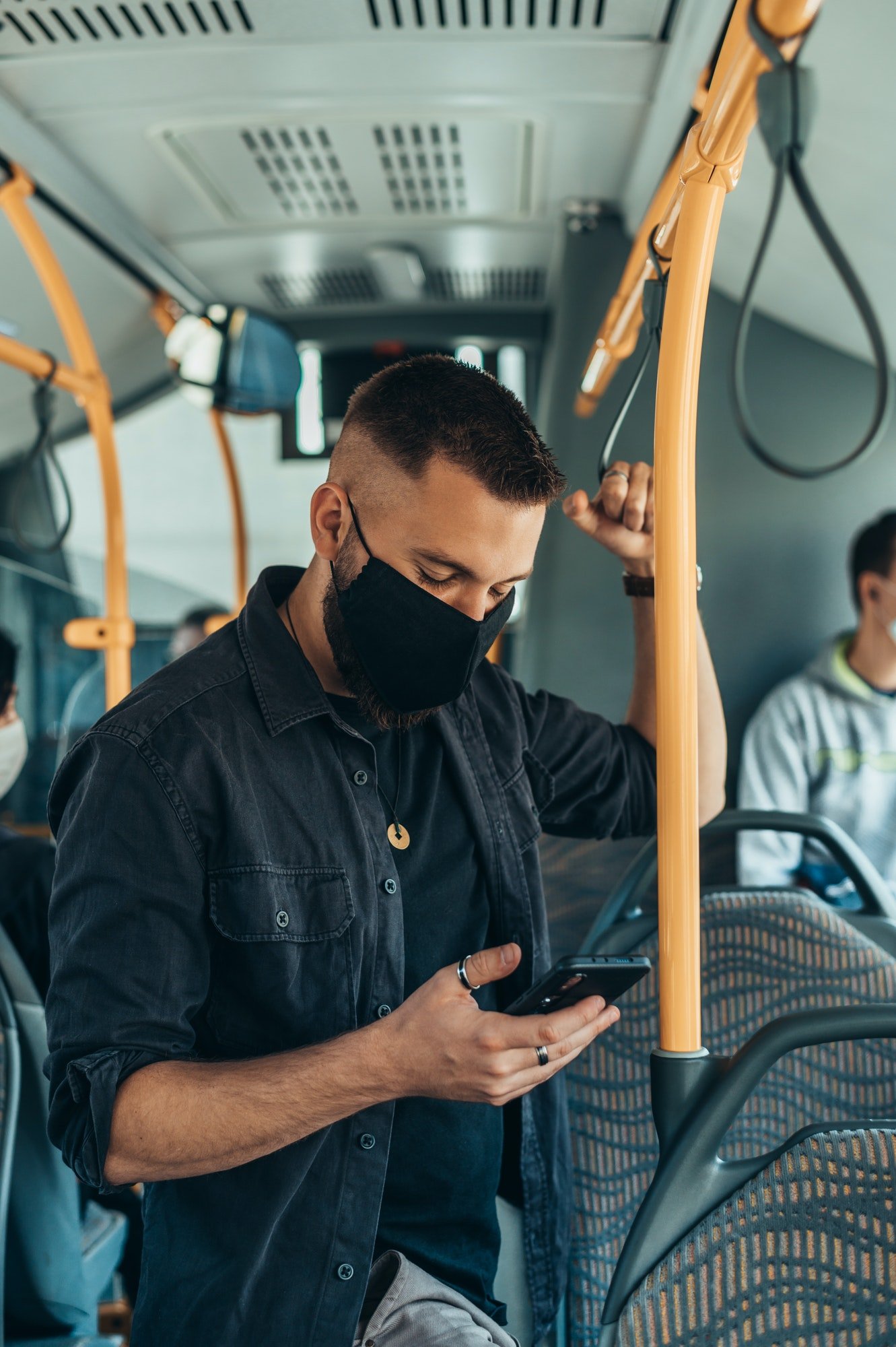 man-wearing-a-protective-mask-and-using-a-smartphone-while-keeping-the-distance-in-the-bus.jpg